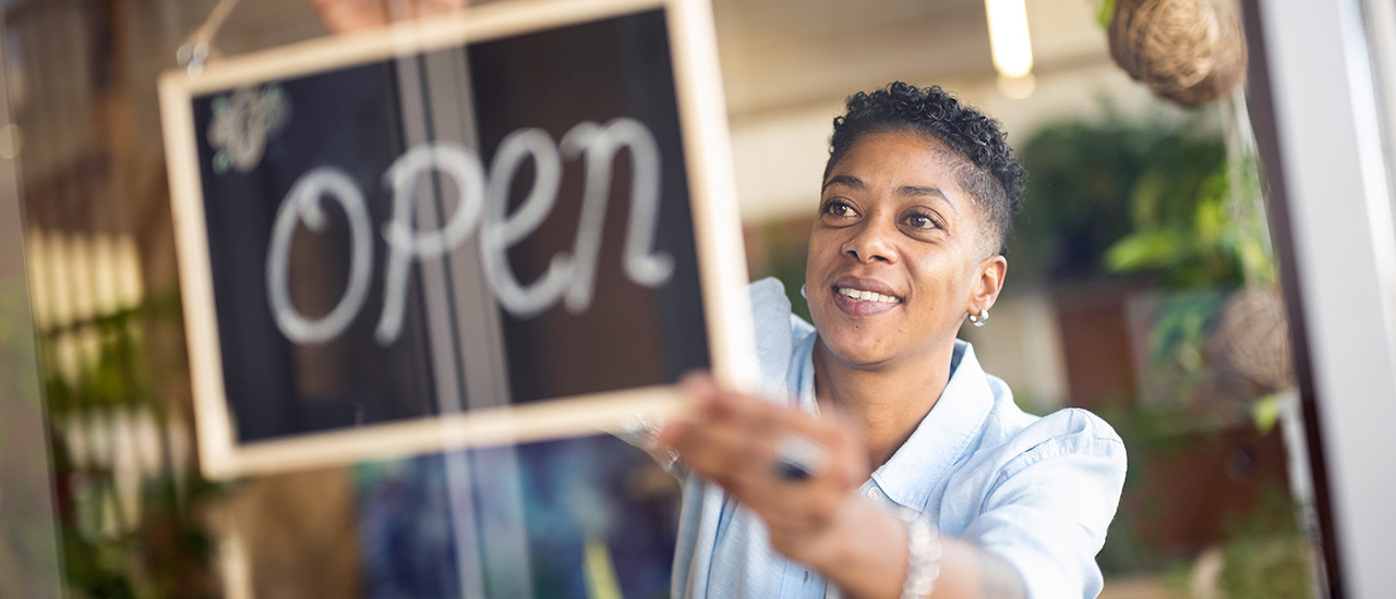 shop owner hangs an open sign on the door