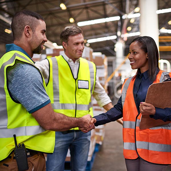 A man and a woman shake hands on the factory floor