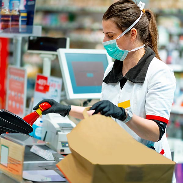 Cajera con una mascarilla y guantes trabajando en la caja registradora.